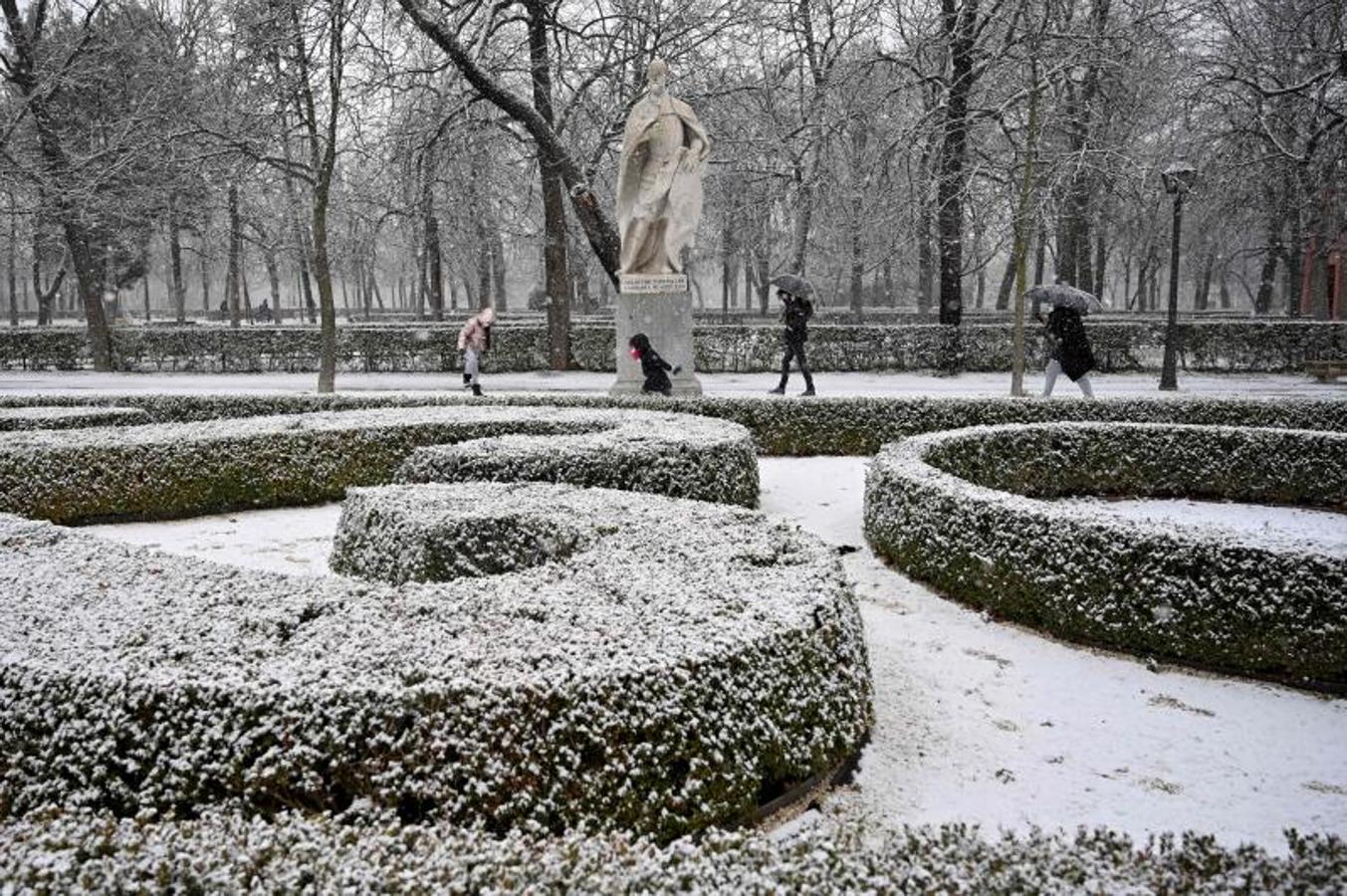 La gente camina mientras la nieve cae en el Parque del Retiro, en Madrid.