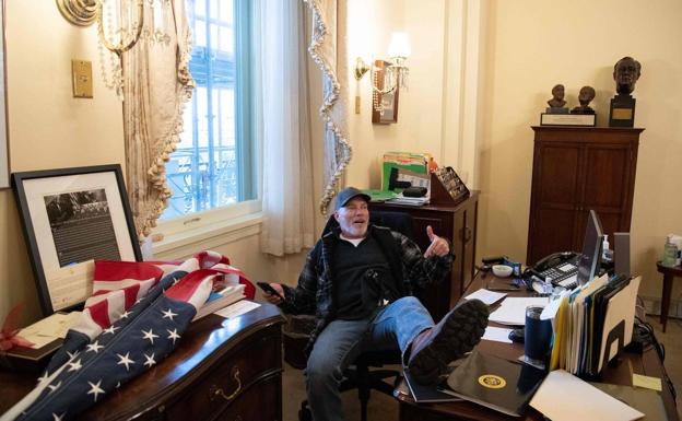 Richard Barnett, uno de los seguidores de Trump que asaltaron el Capitolio, pone su bota encima de la mesa del despacho de Nancy Pelosi.