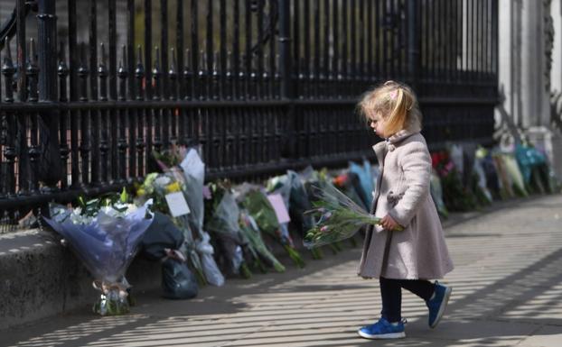 Una niña deja unas flores en recuerdo de Felipe de Edimburgo. 