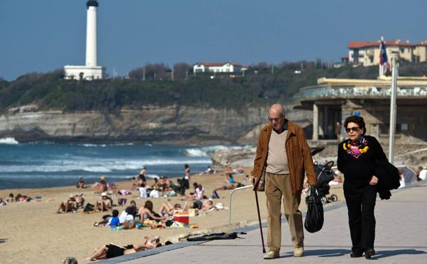 Dos jubilados paseando frente a una playa. /r. c.