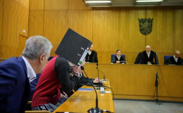 El condenado, Taha al J.. oculta la cara tras una carpeta durante el juicio.