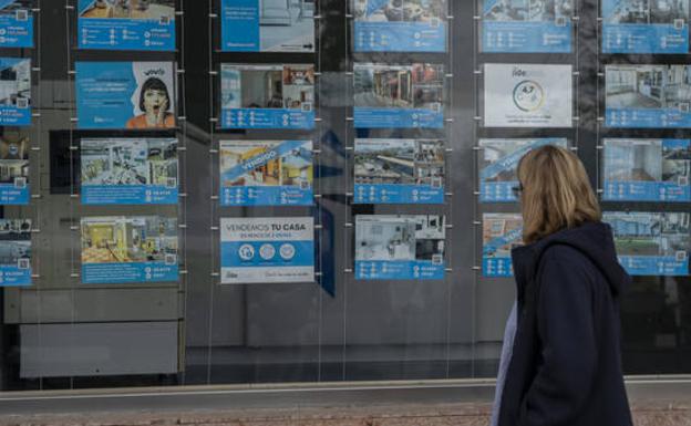 A citizen observes a house for sale poster. 