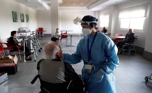 A worker in a nursing home does an antigen test on an elderly man. 