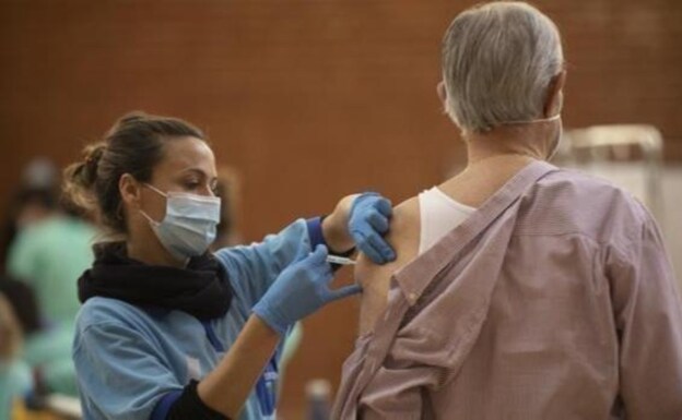Una sanitara vacuna a un mayor en un hospital de Sevilla. 