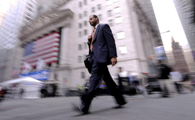 A citizen walks in front of the facade of the New York Stock Exchange. 