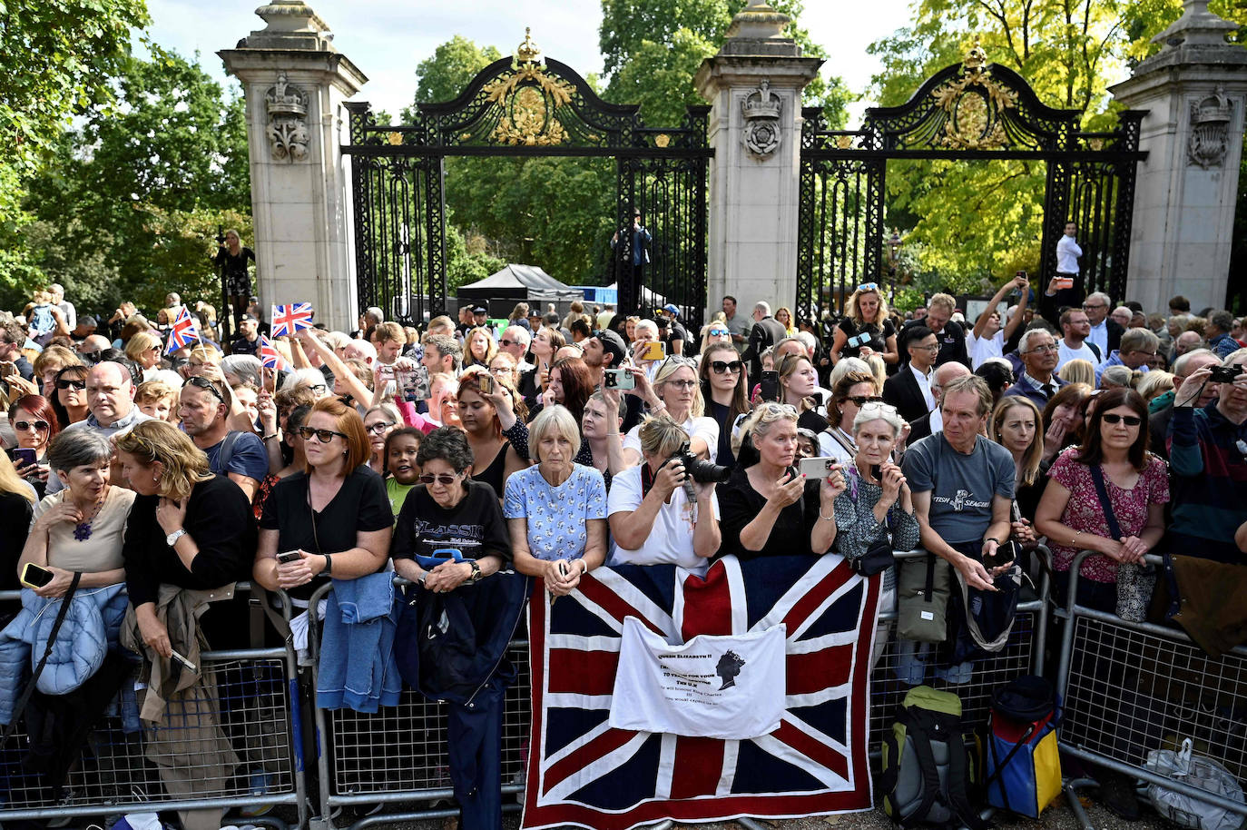 Un grupo de personas aguarda en una calle de Londres al féretro de la reina.