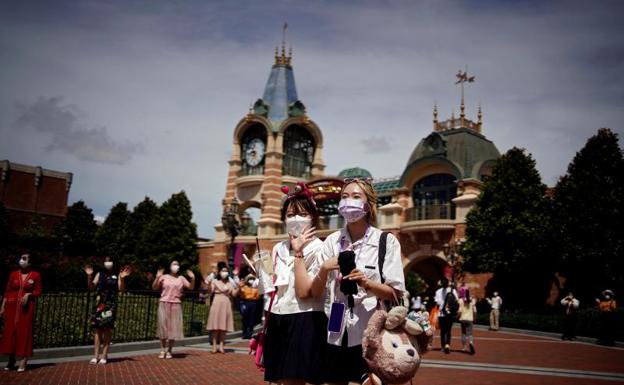 Dos jóvenes, con mascarilla, en Disneyland Shanghái. 