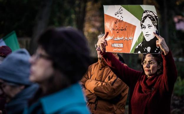 Una mujer sostiene un cartel en apoyo a Mahsa Amini durante una manifestación frente a la Cámara de Representantes en La Haya. /AFP